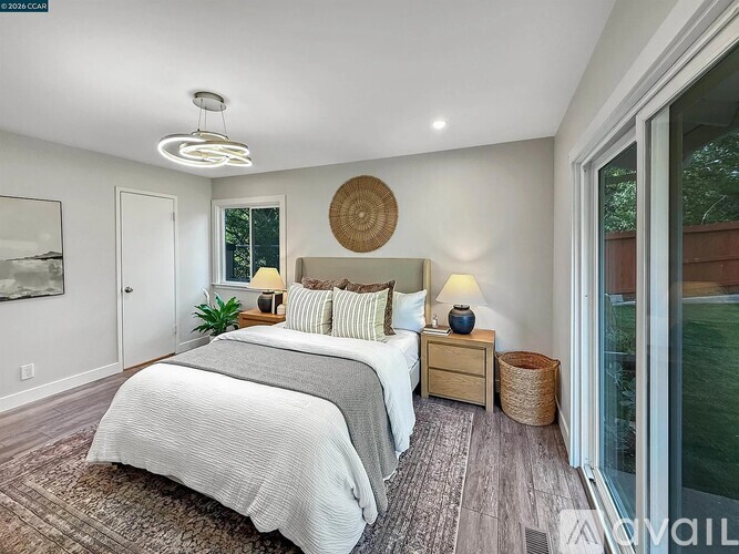 A bedroom with a large bed and a window overlooking a backyard.