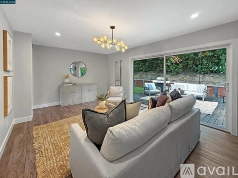 A living room with a grey couch and a chandelier.