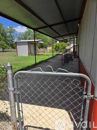 A chain link fence with a gate is in front of a building.