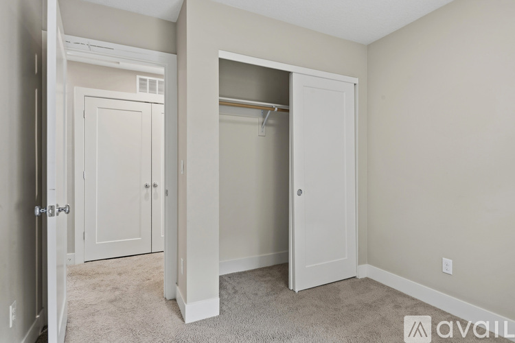 A bedroom with a white door and a white closet.