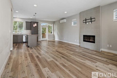 A spacious living room with wood flooring and a fireplace.