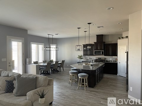 A modern kitchen with a bar stool and a dining table with chairs.