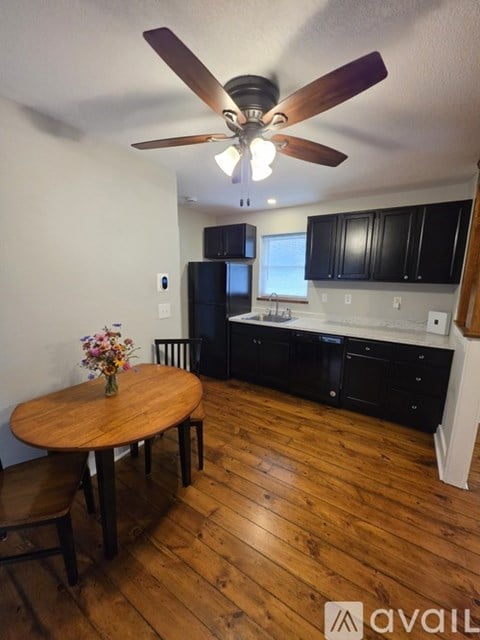 A kitchen with a wooden table and chairs and a ceiling fan.