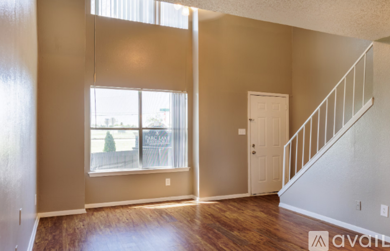 A room with a staircase and a window showing a view of a fence and trees.