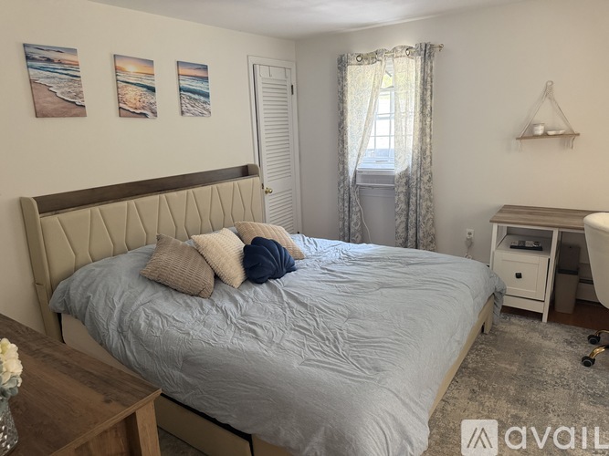 A bedroom with a large bed and a desk with a lamp.