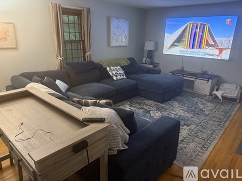A living room with a blue couch and a shelf with a lamp on it.