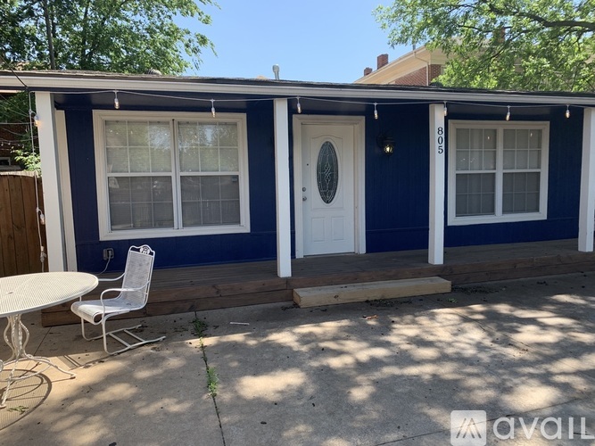 A blue house with a white door and a white chair outside.