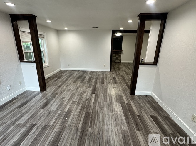 A spacious room with wood flooring and white walls.
