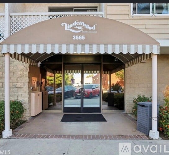 The entrance to a building with awn that reads "Vinewood" and a phone number.