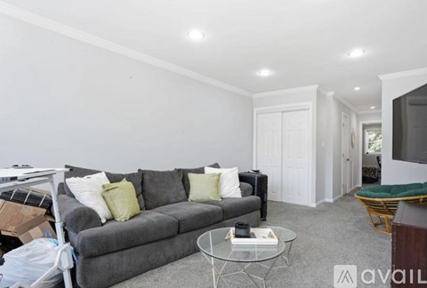 A living room with a grey couch and a glass coffee table.