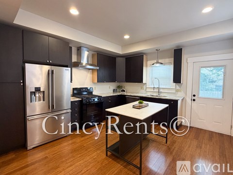 A modern kitchen with black cabinets and stainless steel appliances.
