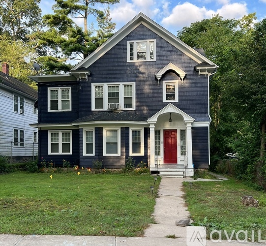 A blue house with a red door and a white porch.