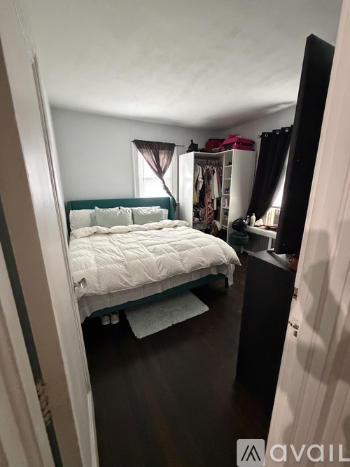 A bedroom with a bed, a wardrobe, and a window with curtains.