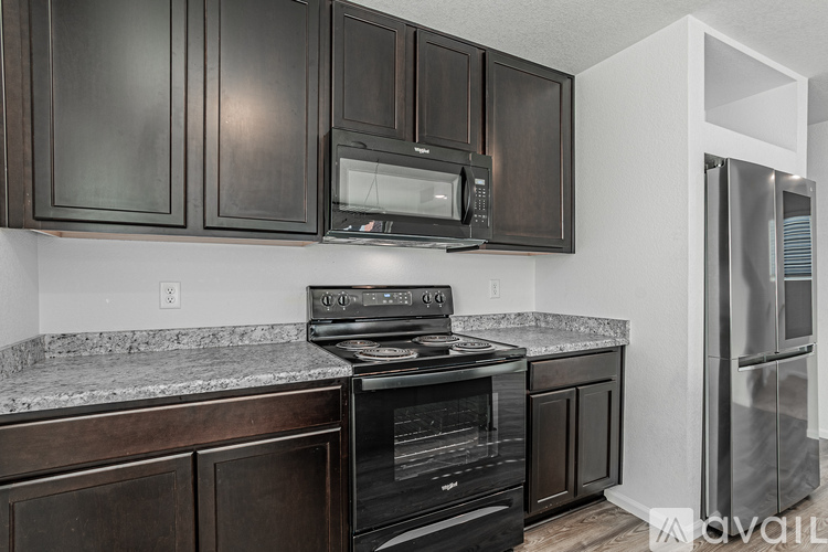 A kitchen with dark brown cabinets and a granite countertop.