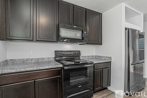 A kitchen with dark brown cabinets and a granite countertop.