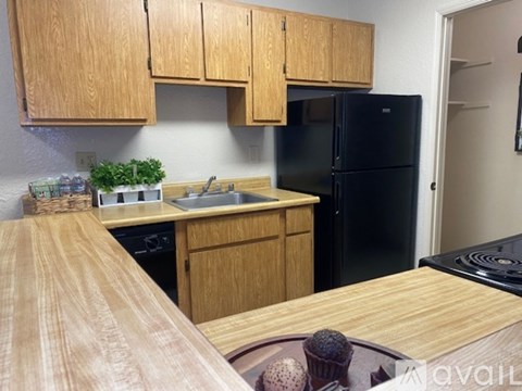 A kitchen with wooden cabinets and a black refrigerator.