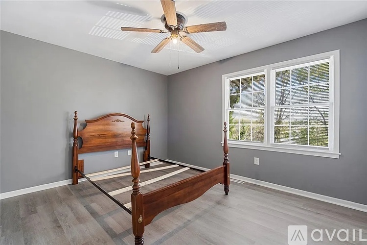 A bedroom with a bed, a ceiling fan, and a window.