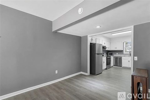 A kitchen with a refrigerator, oven, and cabinets is visible from the living room.