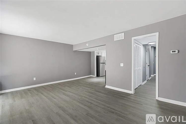 A spacious room with wood flooring and a doorway leading to another room.