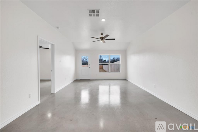 A spacious room with a ceiling fan and a view of the outdoors through the windows.