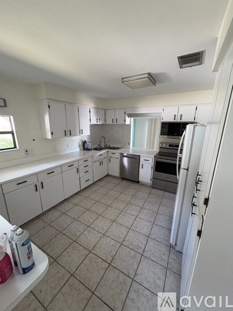 A kitchen with white cabinets and a tile floor.