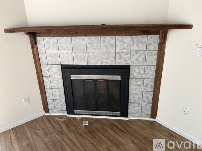 A fireplace with a wooden mantle and a black screen door.