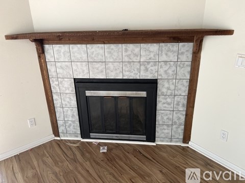 A fireplace with a wooden mantle and a black screen door.