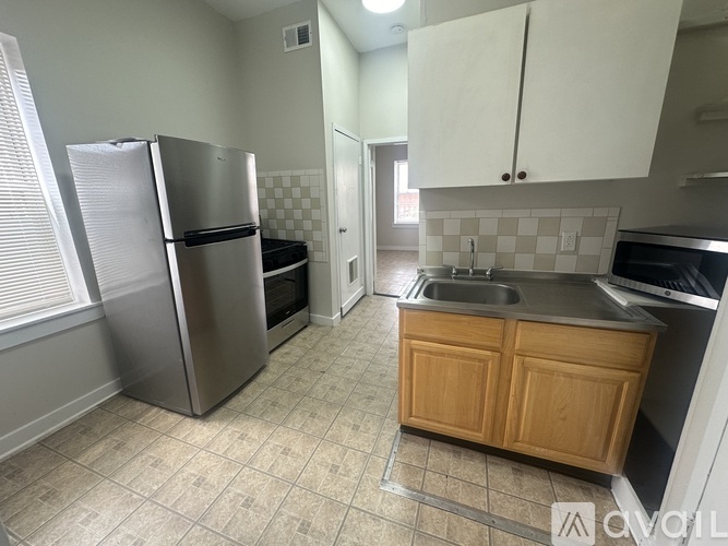 A kitchen with a stainless steel refrigerator and wooden cabinets.