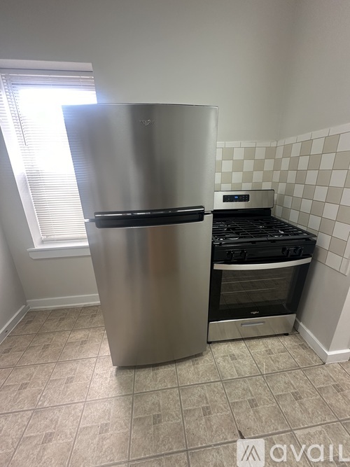 A stainless steel refrigerator in a kitchen with a tiled backsplash.