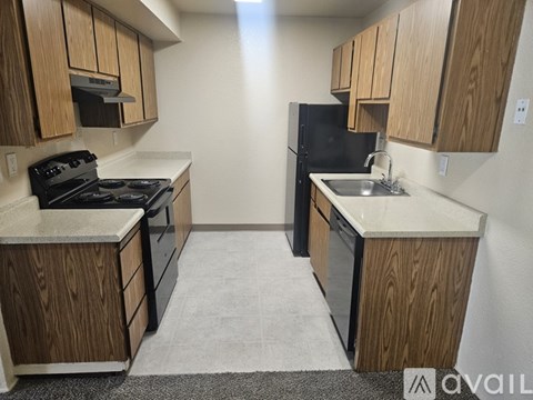 A kitchen with a black refrigerator and wooden cabinets.