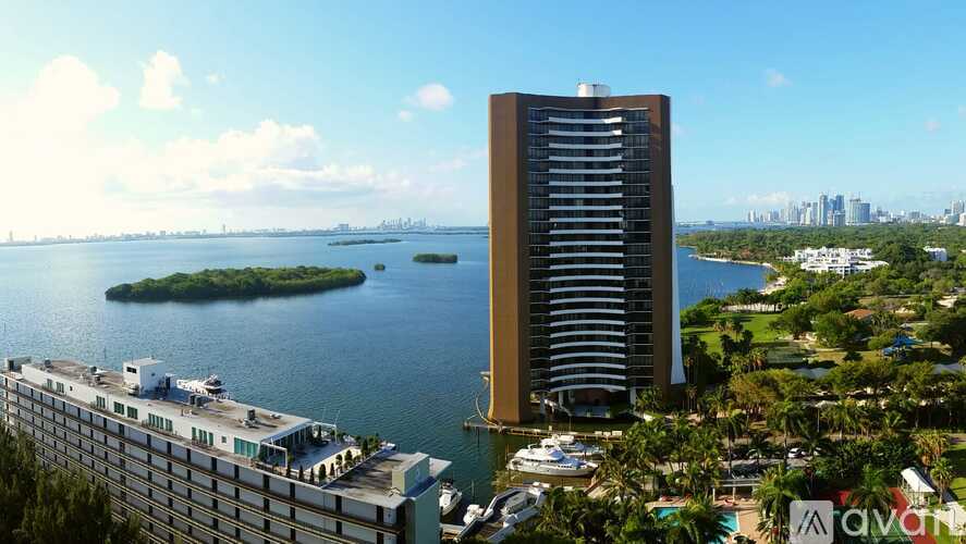 A tall building stands next to a body of water with boats docked nearby.