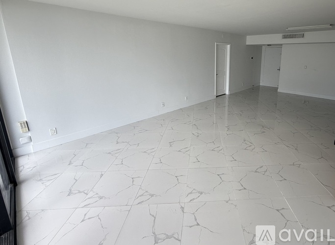 A spacious room with white marble flooring and walls.
