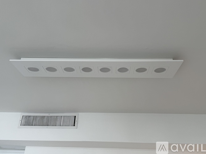 A white ceiling with a vent and a row of circular holes.