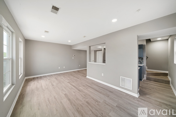 A spacious room with wooden flooring and a large window on the left.