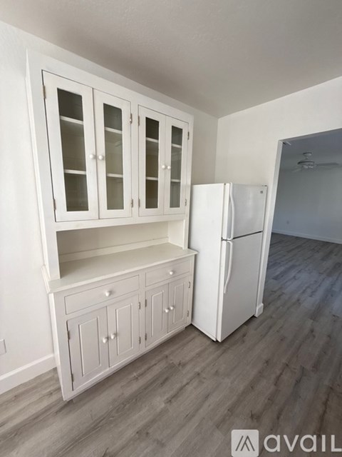 A kitchen with white cabinets and a white refrigerator.