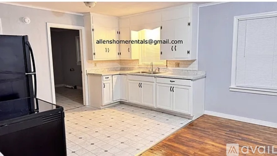 A kitchen with white cabinets and a black refrigerator.