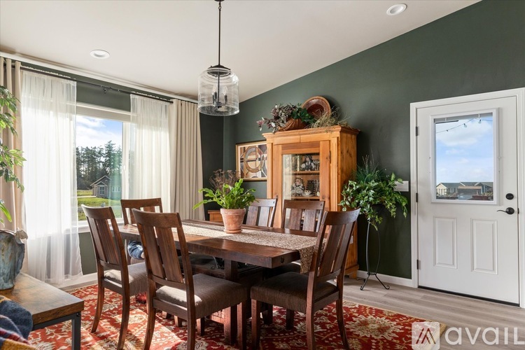 A dining room with a table set for four and a view of the backyard.