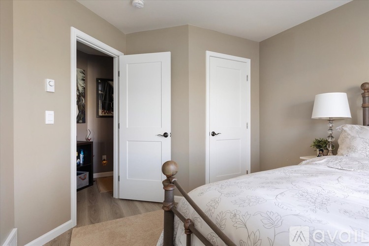 A bedroom with a large bed and a doorway leading to another room.
