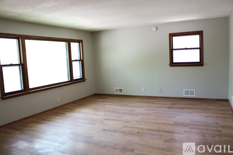 A room with wooden floors and two windows.
