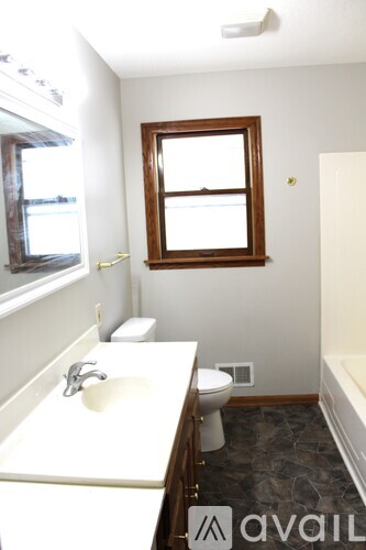 A bathroom with a toilet, sink, and window.