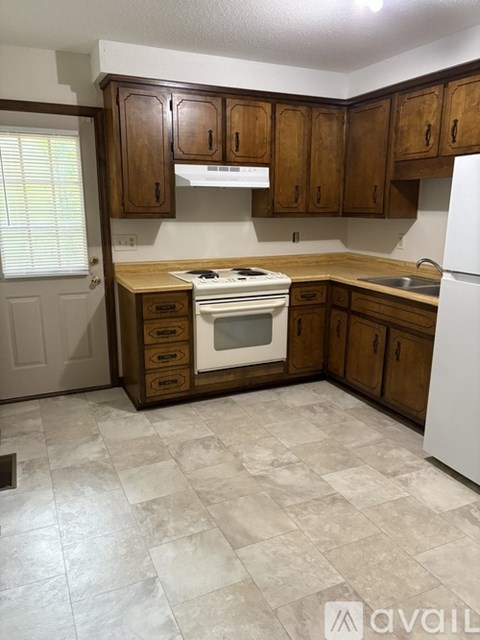 A kitchen with brown cabinets and a white refrigerator.