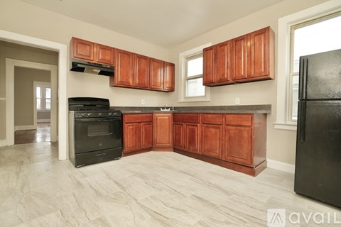 A kitchen with wooden cabinets and a black refrigerator.