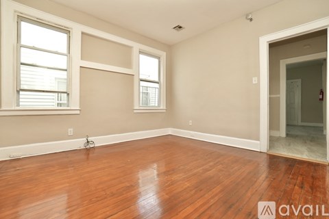 A room with wooden floors and two windows.