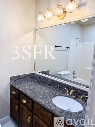 A bathroom with a granite countertop and a large mirror.