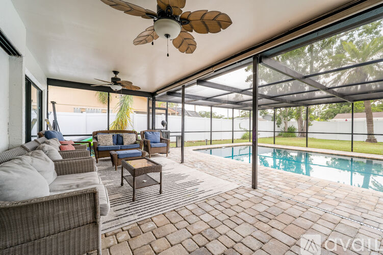 A patio with a ceiling fan and a pool in the background.