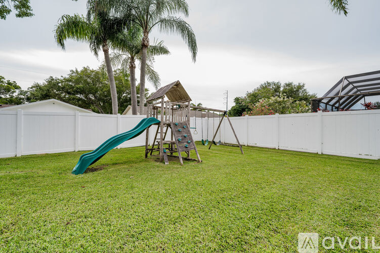 A playground with a green slide and a wooden swing set.