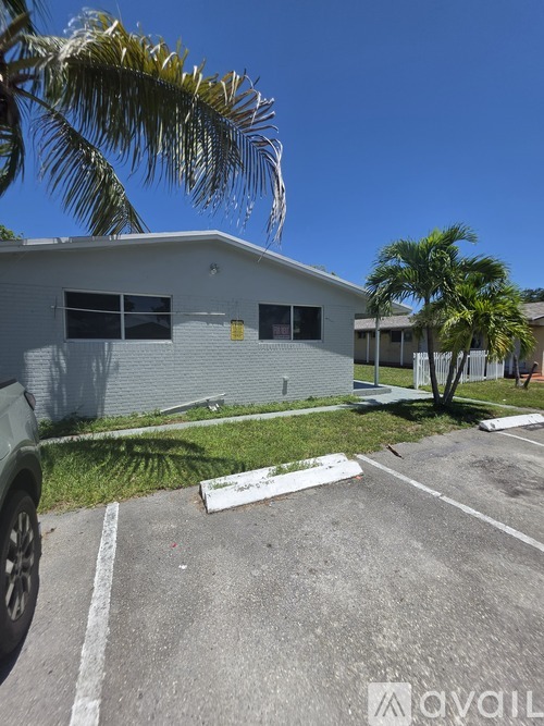 A parking lot with a building and palm trees in the background.