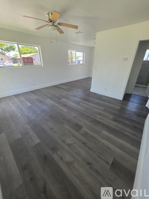 A room with a ceiling fan and wood flooring.