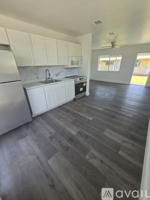 A kitchen with white cabinets and a wooden floor.