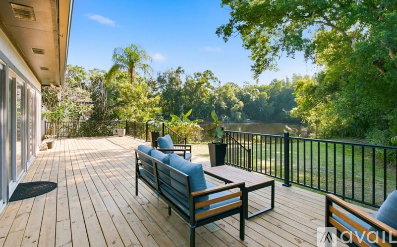 A wooden deck with a bench and a table surrounded by trees.